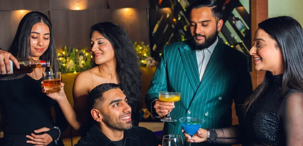 Friends raising cocktails together at a table in the dining room