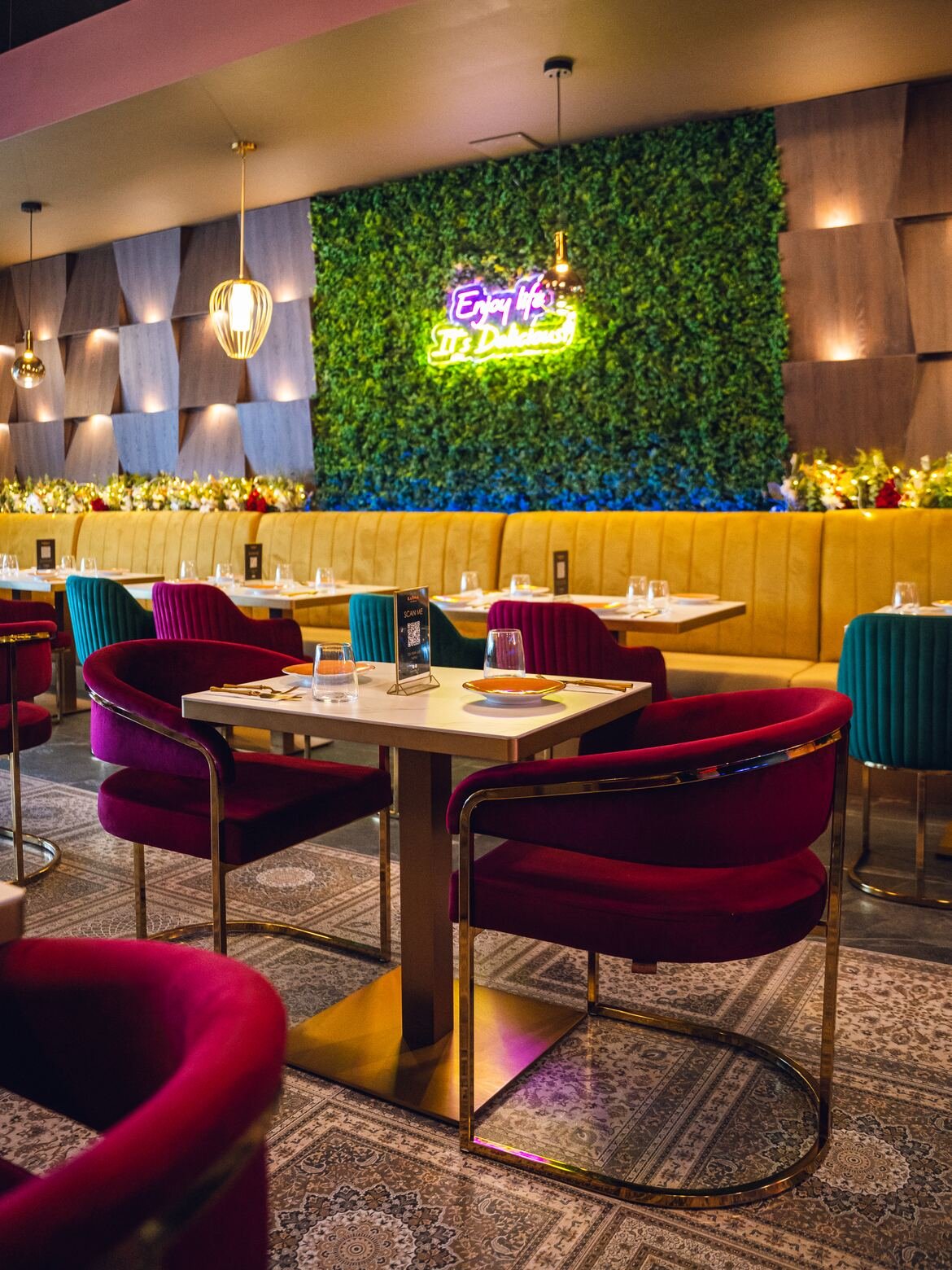 Karma bistro dining room with jewel-toned chairs and a living green wall