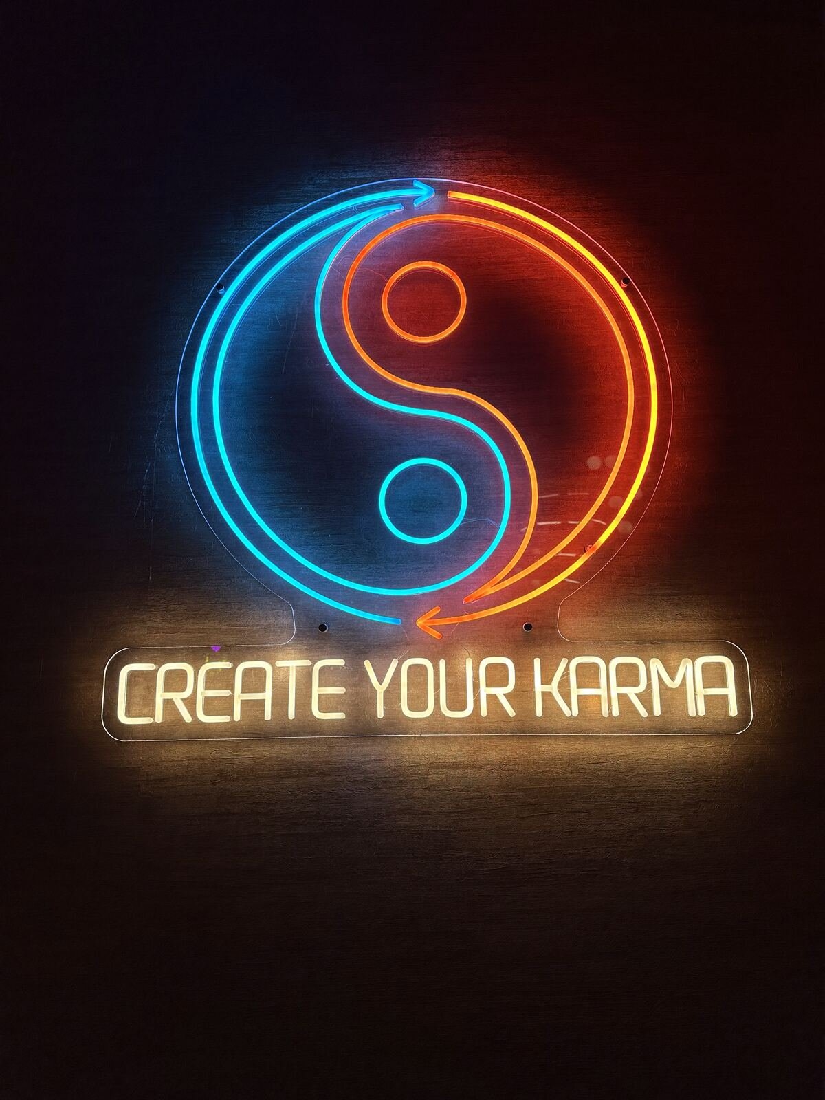 Neon yin-yang sign reading ‘Create Your Karma’ in the Karma dining room